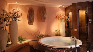 A modern bathroom with a freestanding bathtub, decorative wall art, and potted plants. - Merry Season Motel (Kaohsiung)