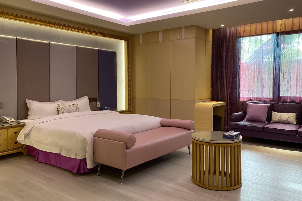 Une chambre moderne avec un grand lit, des tables de chevet, un canapé et une table basse ronde.