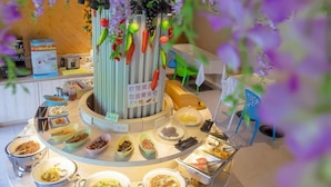 A buffet setup with various food items and a central decorative column. - Merry Season Motel (Kaohsiung)