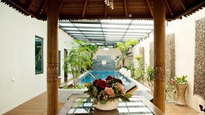A covered outdoor area with a pool, wooden pillars, and potted plants. - Merry Season Motel (Kaohsiung)
