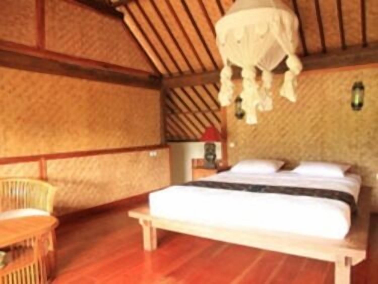 Une pièce en bois avec un lit, une chaise et un luminaire suspendu.