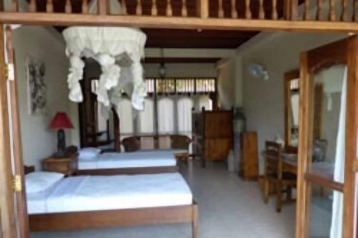 Una habitación con dos camas, un armario de madera, un escritorio y una silla.