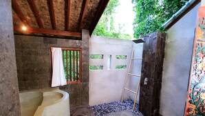 Un baño con un lavabo de piedra, zona de ducha y una ventana con cortina.