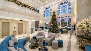 Un vestíbulo amplio con un gran árbol de Navidad, asientos cómodos y un techo alto con iluminación decorativa.