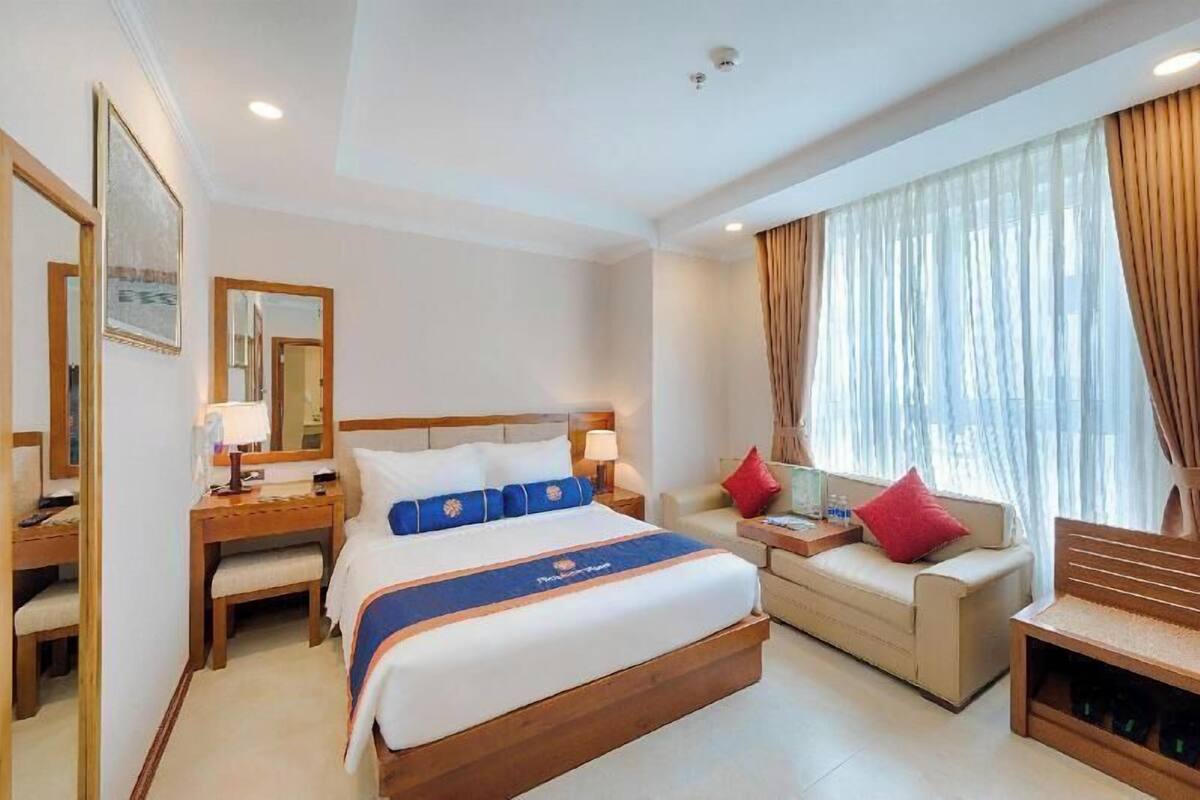 A hotel room with a bed, a sofa, a desk, and a chair.