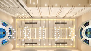 Un interior amplio con techo alto, luminarias modernas y vidrieras de colores.