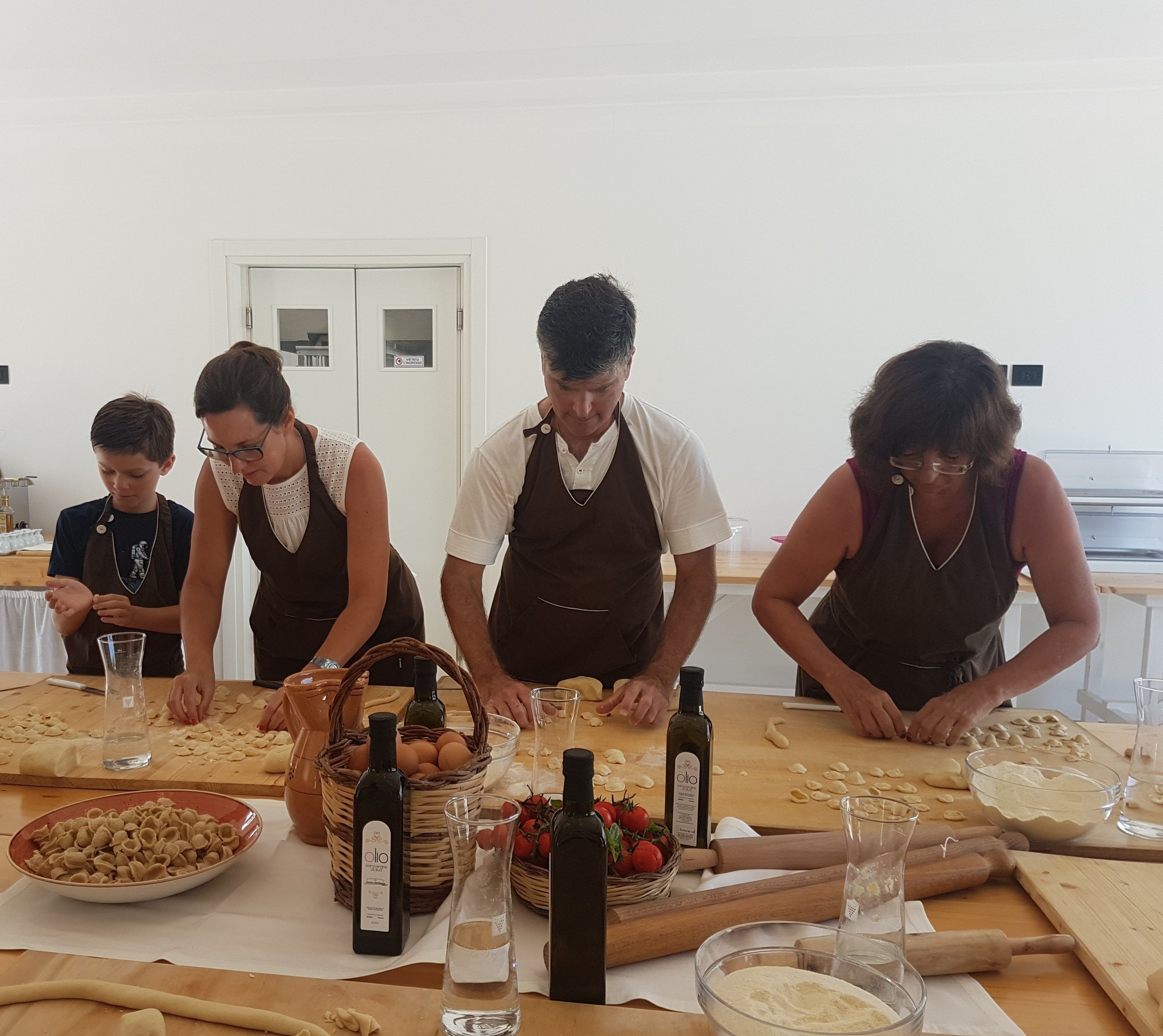 A group of people engaged in food preparation, with various ingredients and kitchen tools on the table.