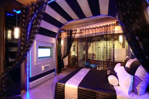 A modern bedroom with a large bed, a TV, and a glass shower area. - Shinyseasons Motel (Kaohsiung)