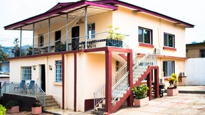 A two-story building with a balcony, a staircase, and potted plants. - Jam Lodge (Freetown)