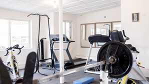 A gym with exercise equipment, including a treadmill, stationary bike, and weight bench. - Jam Lodge (Freetown)