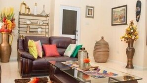 A living room with a leather sofa, a glass coffee table, and a decorative rug.