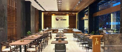 A restaurant with a long counter, multiple tables, and chairs.