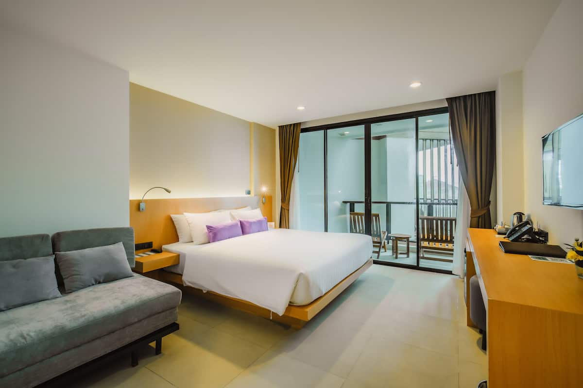 Une chambre d’hôtel avec un lit, un canapé, un bureau et un balcon offrant une vue.