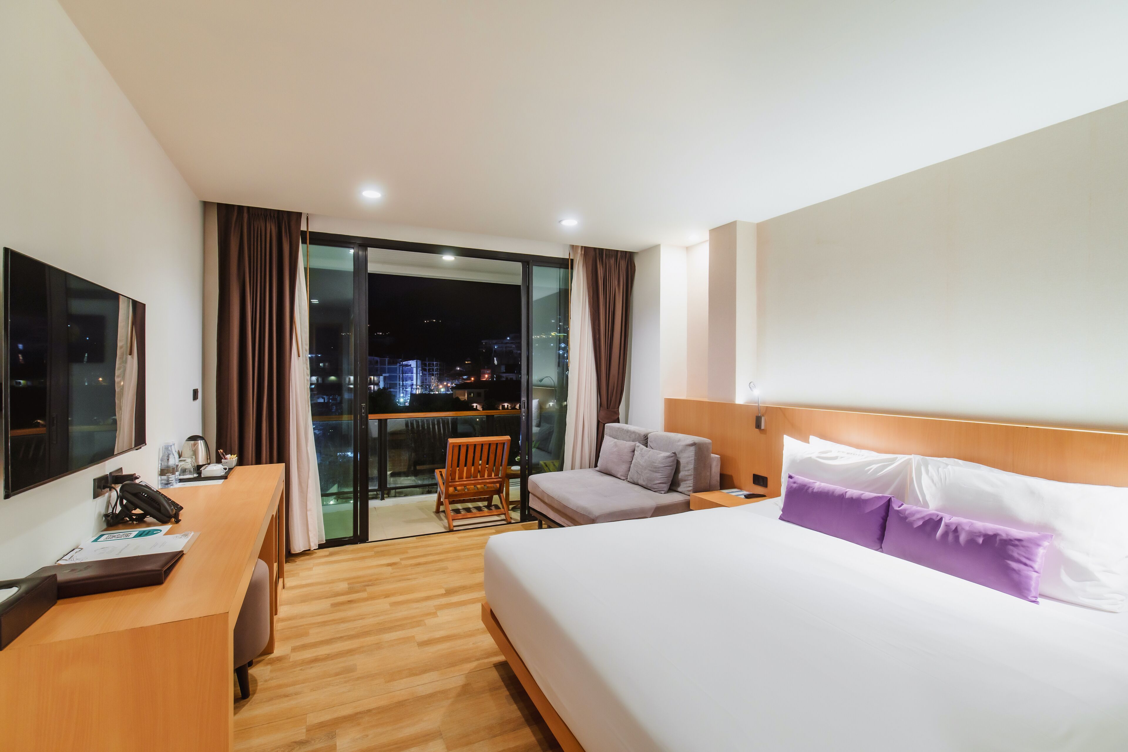 Habitación de hotel con cama, escritorio, silla y vista a la ciudad de noche.