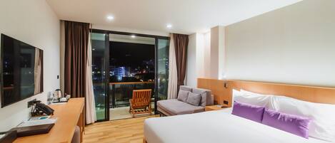 Habitación de hotel con cama, escritorio, silla y vista a la ciudad de noche.