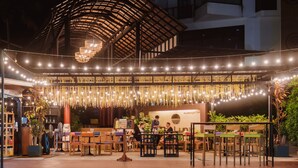 An outdoor dining area with tables and chairs, a covered seating area, and string lights. - The Lunar Patong (Patong)