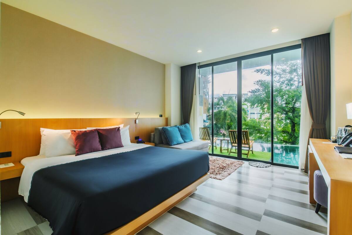 Une chambre d’hôtel moderne, dotée d’un grand lit, d’un bureau et offrant une vue sur l’extérieur.