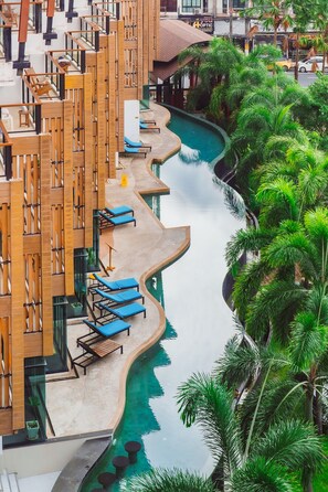 A modern hotel with a pool, lounge chairs, and palm trees. - The Lunar Patong (Patong)