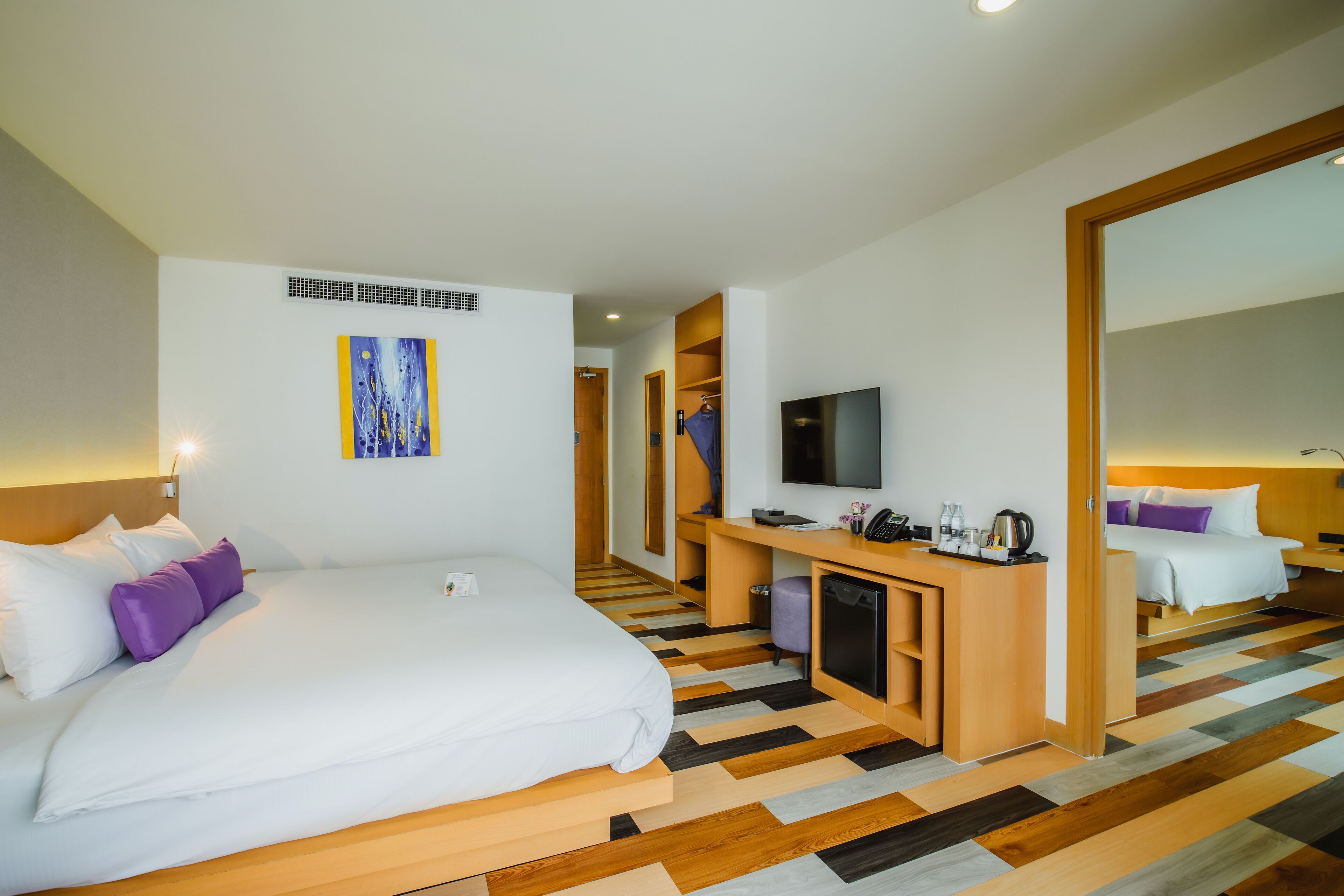 Ein Hotelzimmer mit einem großen Bett, einem Schreibtisch mit Fernseher und einem Kleiderschrank.