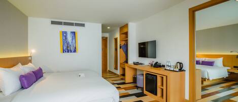 Ein Hotelzimmer mit einem großen Bett, einem Schreibtisch mit Fernseher und einem Kleiderschrank.