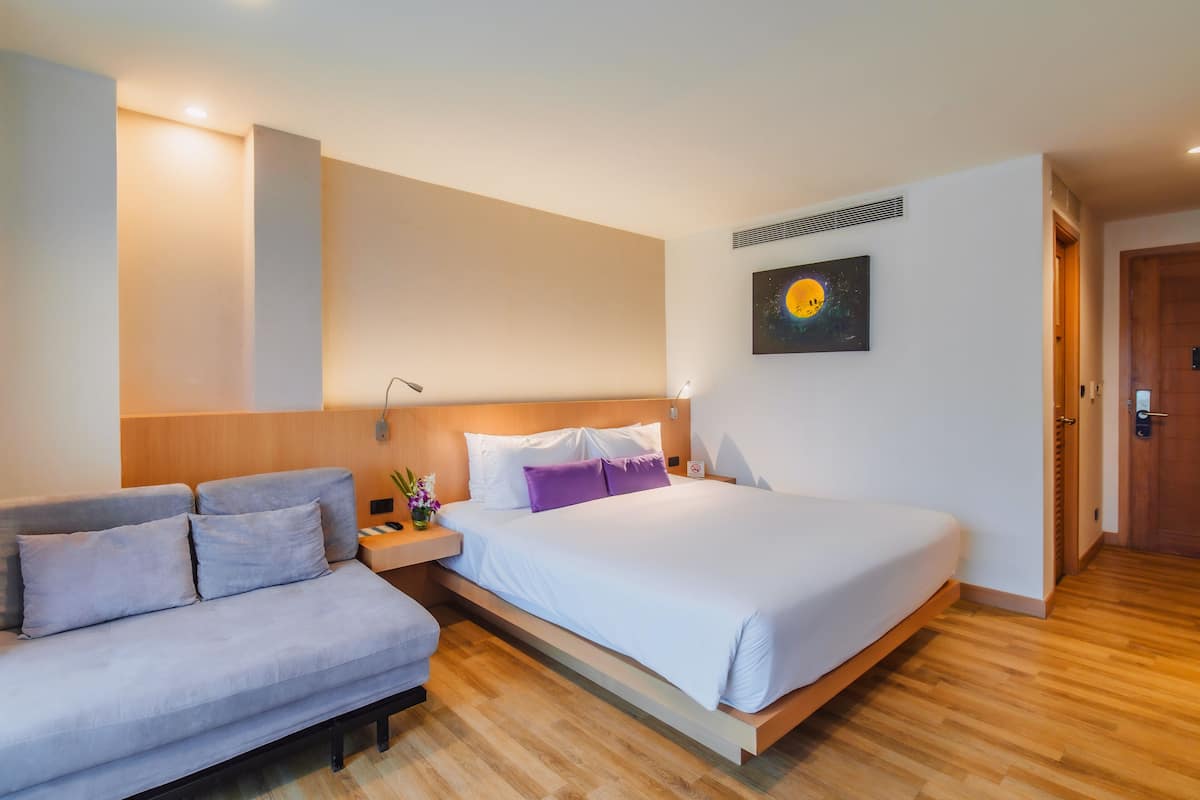 Une chambre d’hôtel moderne, équipée d’un lit, d’un canapé et d’une table de chevet.