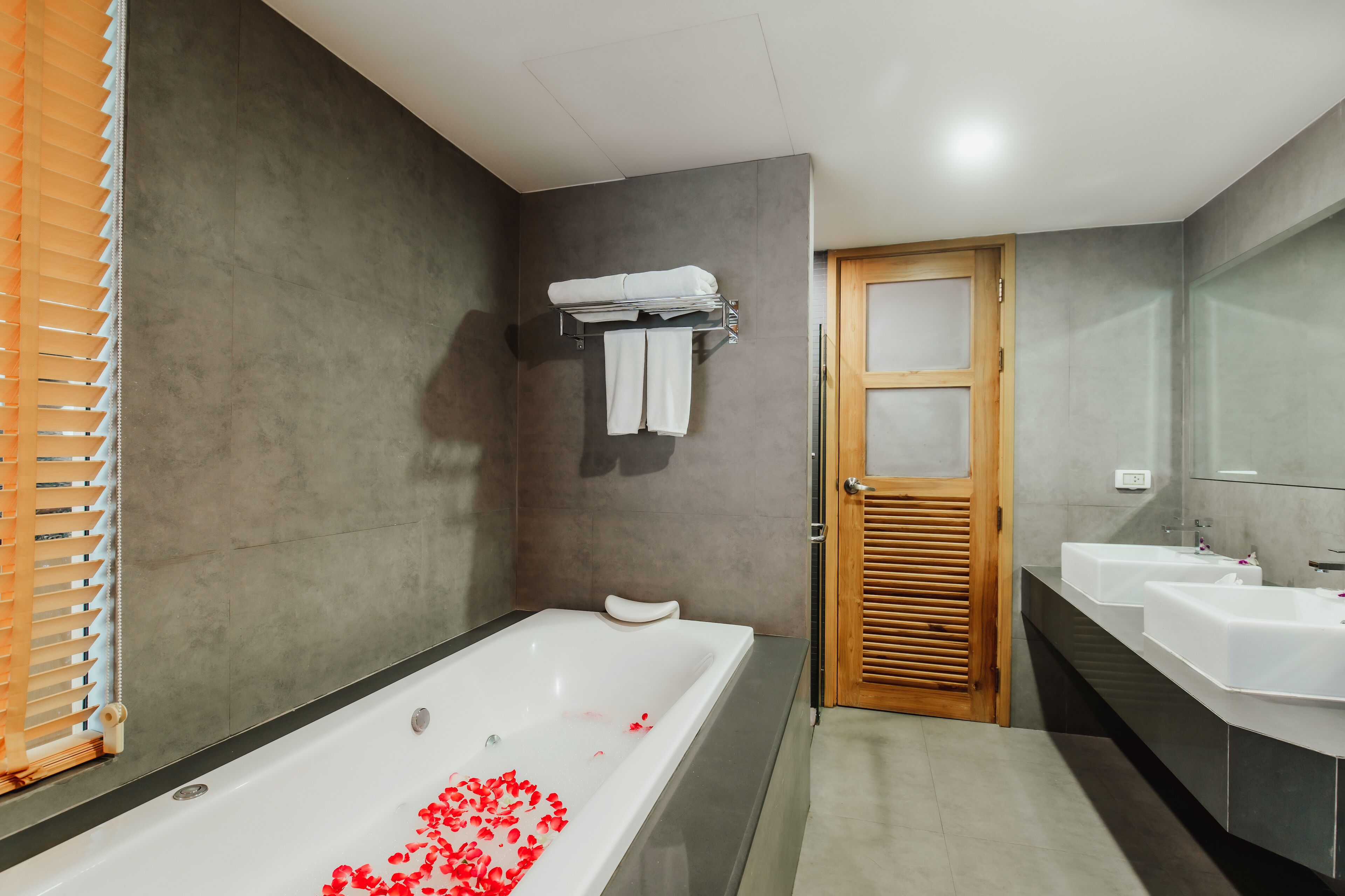 Un baño moderno con bañera, dos lavamanos y una puerta de madera.