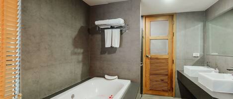 Un baño moderno con bañera, dos lavamanos y una puerta de madera.