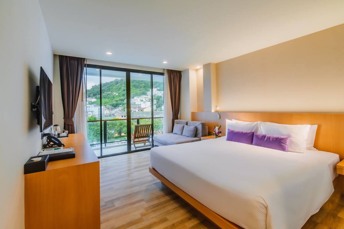 Une chambre d’hôtel avec un grand lit, un bureau, une chaise et un téléviseur.