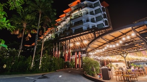A multi-story hotel with a covered outdoor area featuring tables and chairs. - The Lunar Patong (Patong)