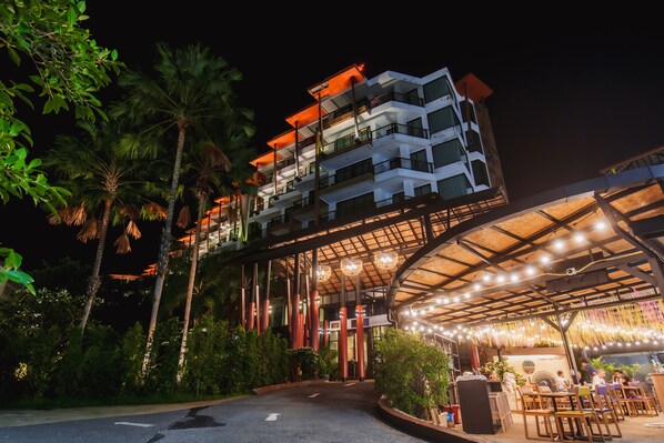 A multi-story hotel with a covered outdoor area featuring tables and chairs. - The Lunar Patong (Patong)