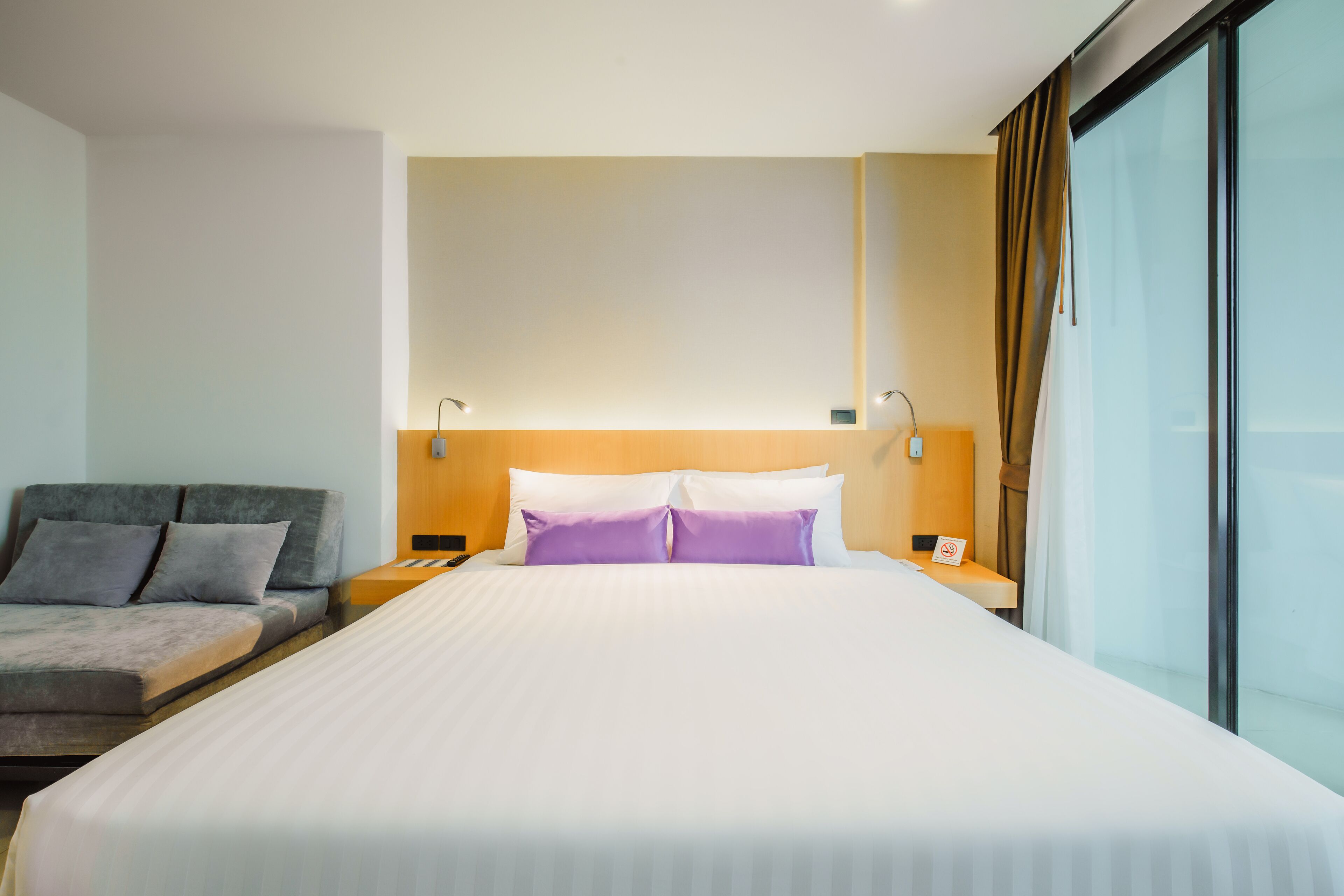 Ein Hotelzimmer mit einem großen Bett, einem Schlafsofa, einem Nachttisch und einem Fenster mit Vorhängen.