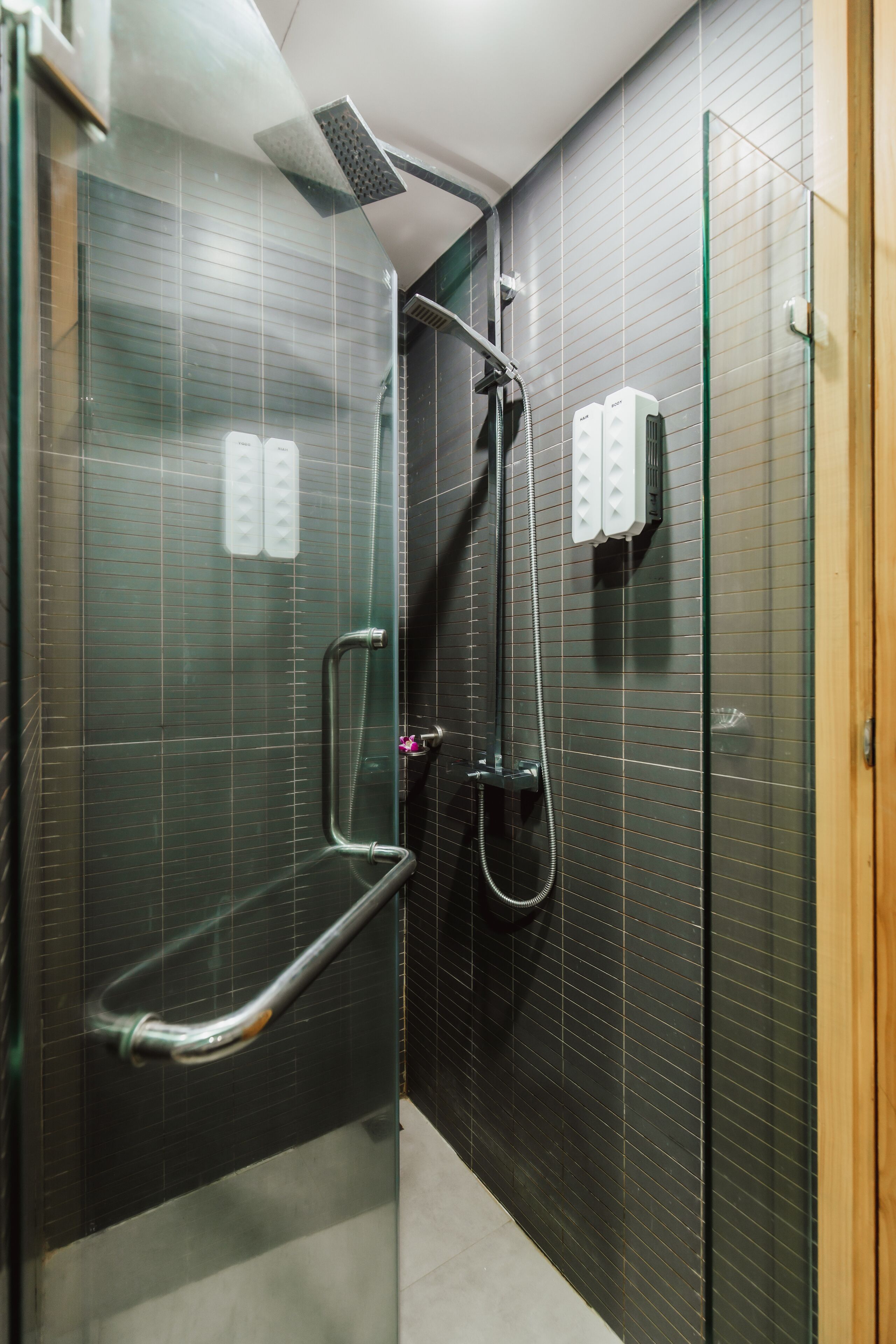 A modern bathroom with a glass shower enclosure, a handheld showerhead, and a handheld shower attachment.