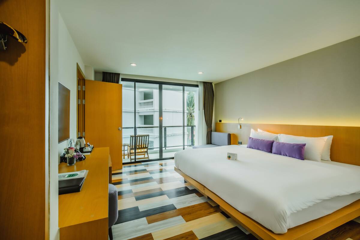 Une chambre d’hôtel dotée d’un grand lit, d’un bureau avec une chaise, d’un balcon avec vue et d’un design moderne.