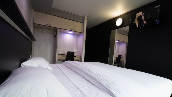 A hotel room with a bed, a desk, and a mirror.