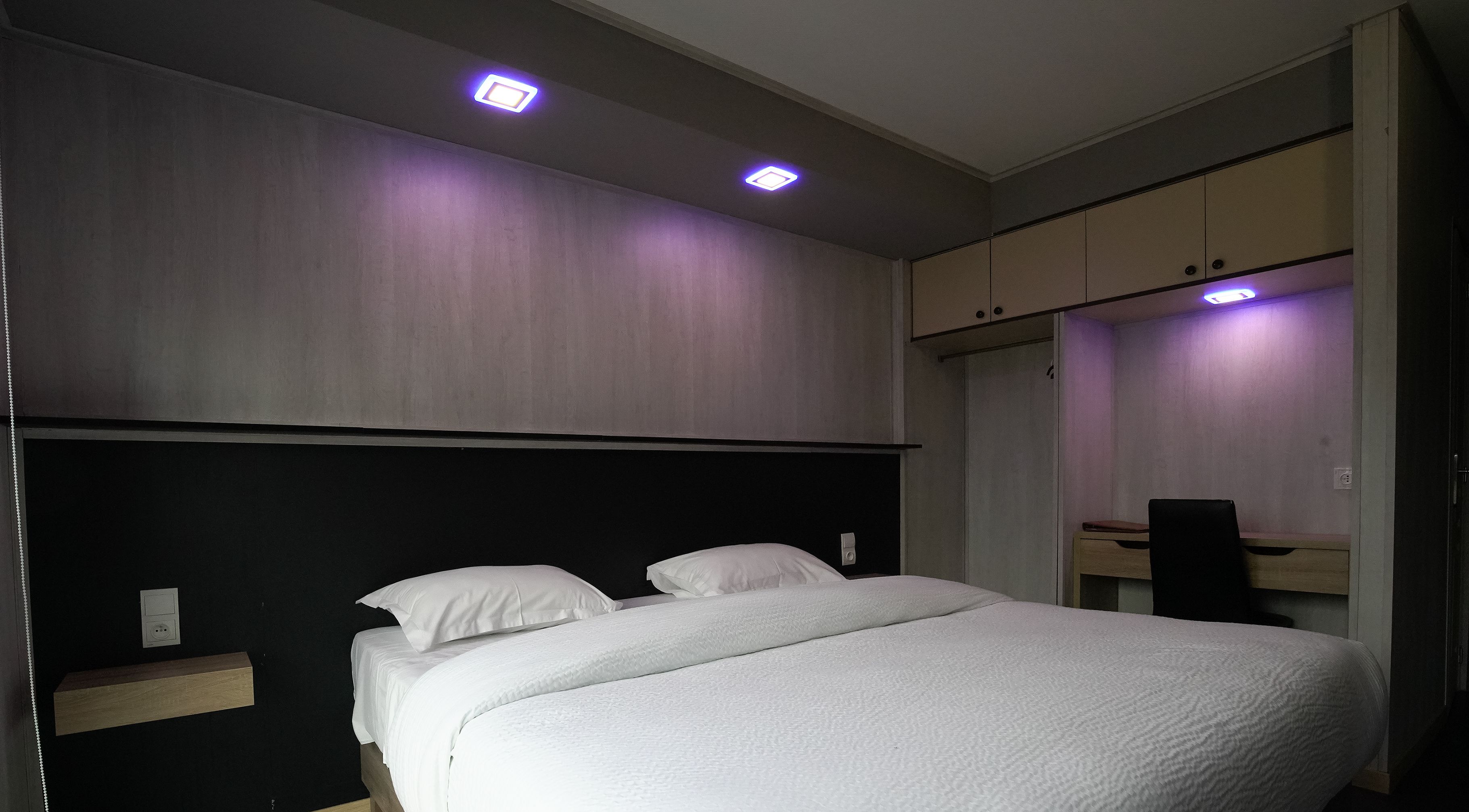 Un dormitorio con cama, mesita de noche, escritorio y armario.
