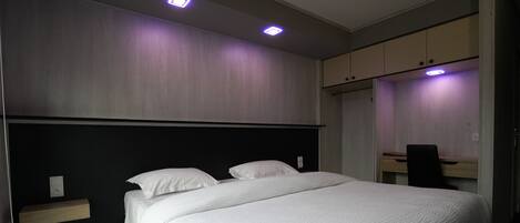 Une chambre à coucher comprenant un lit, une table de chevet, un bureau et une armoire.