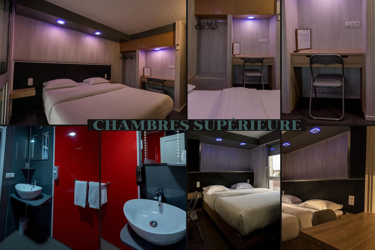 A hotel room with a large bed, a desk, a chair, a bathroom with a sink and mirror, and a red accent wall.