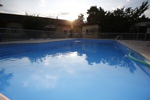Una piscina transparente con cerramiento metálico, rodeada de edificios y árboles.