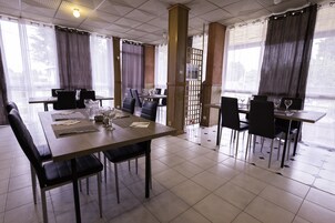 Un comedor con mesas dispuestas para cuatro, cada una con sillas, menús y copas de vino.