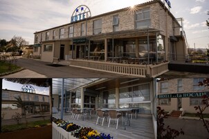 Un hotel con recepción, mobiliario exterior y un balcón.