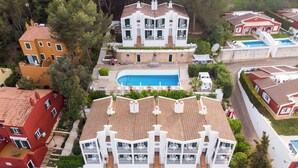Un hotel de varios pisos con piscina, balcones y cancha de tenis.