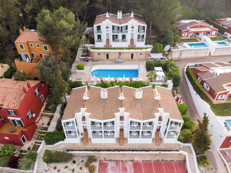 Un hotel de diverses plantes amb piscina, balcons i una pista de tennis.