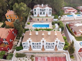 Un hotel de varios pisos con piscina, balcones y cancha de tenis.