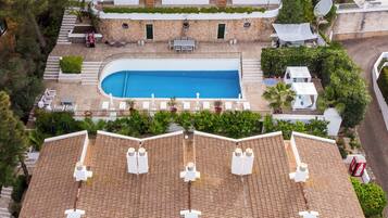 Un edificio de varios pisos con piscina, zona de estar al aire libre y terraza en la azotea.