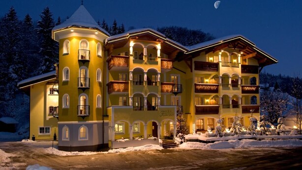 A multi-story hotel with balconies, a snow-covered landscape, and a visible moon in the sky.