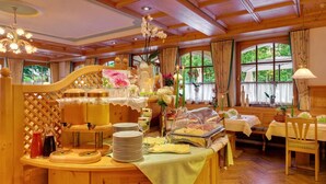 A breakfast buffet setup with a wooden counter, plates, glasses, and a variety of food items.