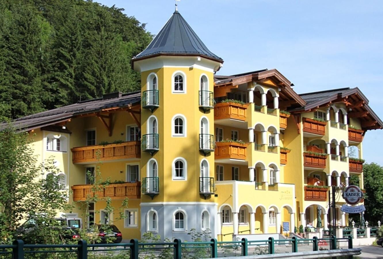 Een hotel met meerdere verdiepingen, balkons, een torenachtige constructie en een bord met 'Kaiser'.