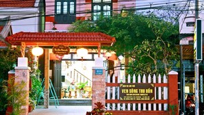 A two-story building with a red-tiled entrance and a signboard. - Thu Bon Riverside Homestay (Da Nang)