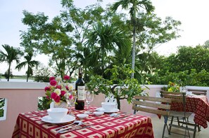An outdoor dining area with a table set for two, featuring a bottle of wine, glasses, and a floral centerpiece. - Thu Bon Riverside Homestay (Da Nang)