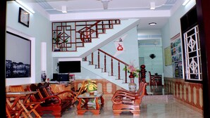 A spacious living area with a staircase, wooden furniture, and a flat-screen TV. - Thu Bon Riverside Homestay (Da Nang)